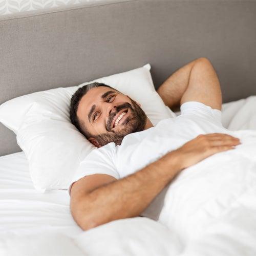 A man smiles while lying in bed