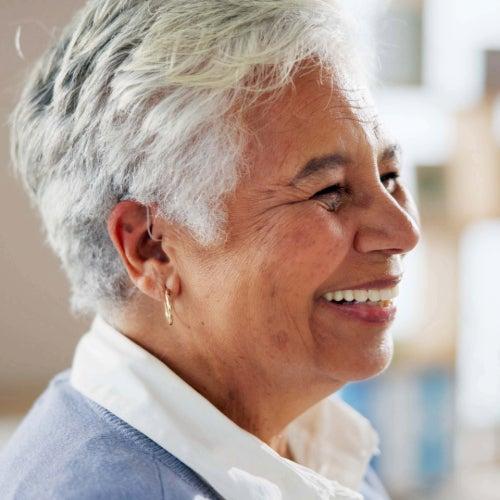 A woman smiling and wearing a hearing aid
