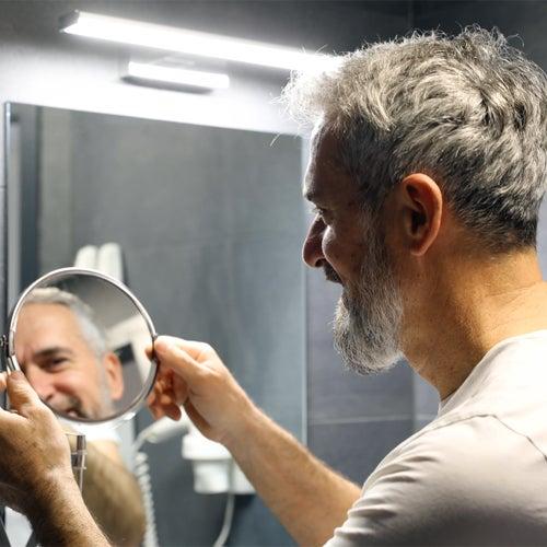 A bearded man looking at himself in a mirror