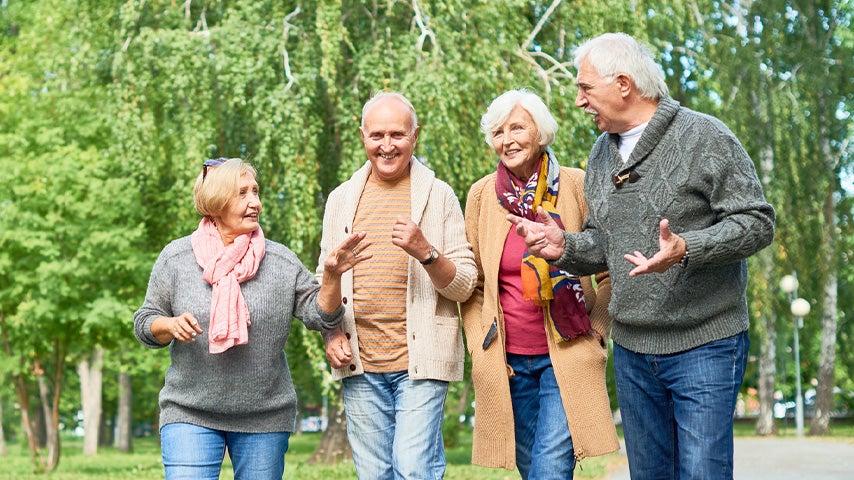 two older women and two older men smiling and talking while walking outside