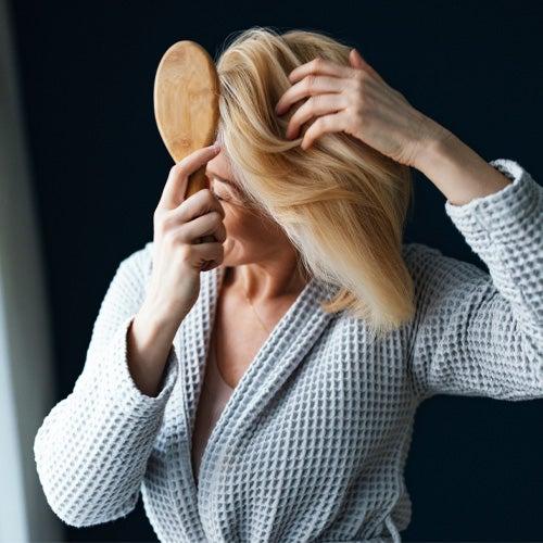 A woman in a bathrobe brushing her hair