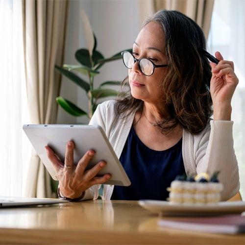 woman wearing glasses and looking at tablet