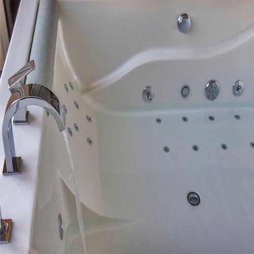 White walk-in tub with many jets and water pouring from a modern faucet
