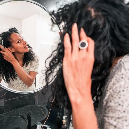 A woman looks in the mirror as she brushes her long, dark hair.