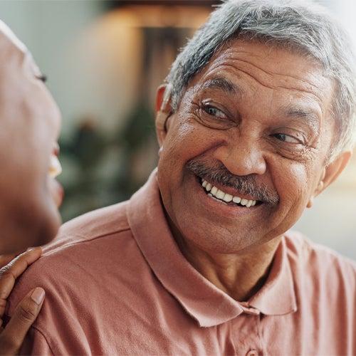 A man wearing a hearing aid and smiling at a woman