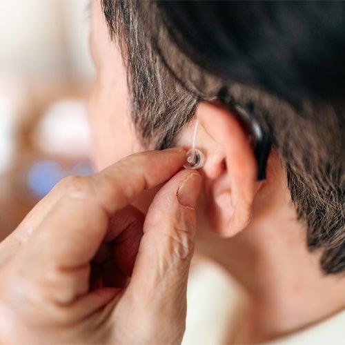 A man wears a receiver-in-canal (RIC) style Lexie hearing aid.