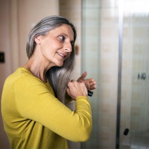 A woman brushing her hair in a bathroom
