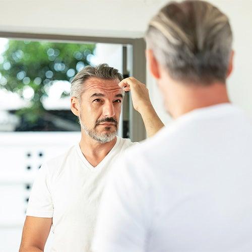 A man looking in the mirror and fixing his hair