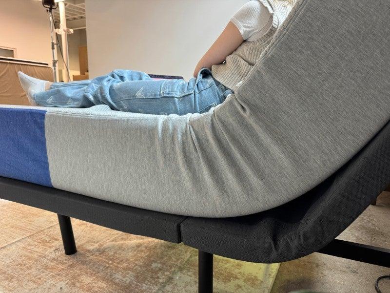 A person resting on the Nectar Adjustable Bed Frame in an upright position