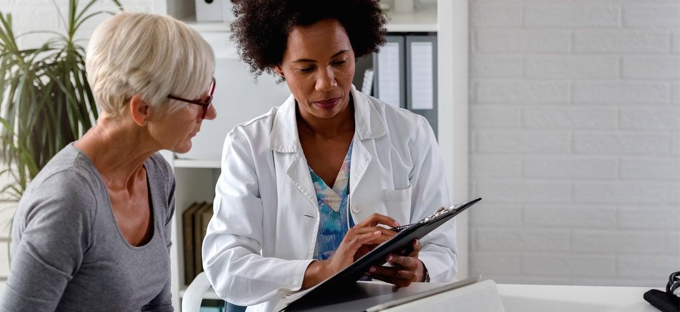 A senior Caucasian woman is listening to her healthcare options from a Black female doctor.