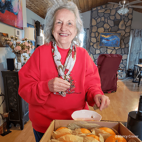 A senior woman wearing a holiday sweater is smiling while getting ready for a holiday dinner with friends and family.
