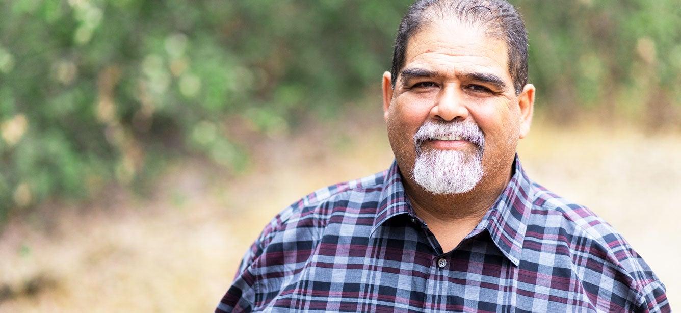 A senior Mexican man is looking confidently at the camera.