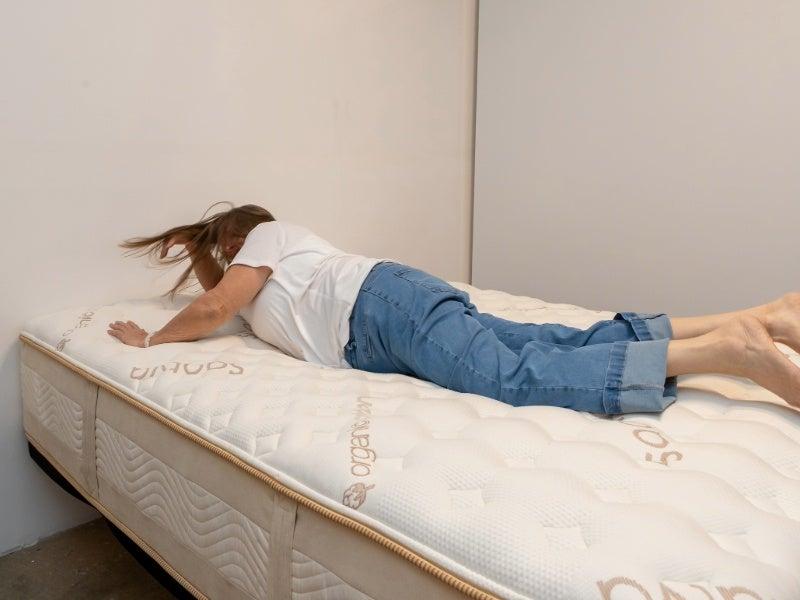 A woman rolling onto her stomach on the Saatva Rx mattress