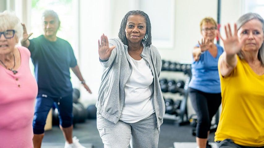A group of people stand in a Tai Chi pose.