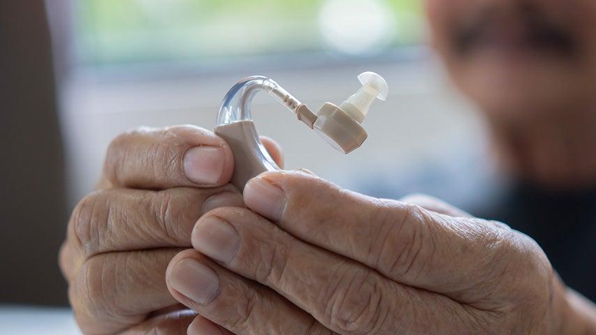 hands holding hearing aid