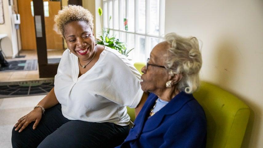 woman smiling at senior center participant on couch