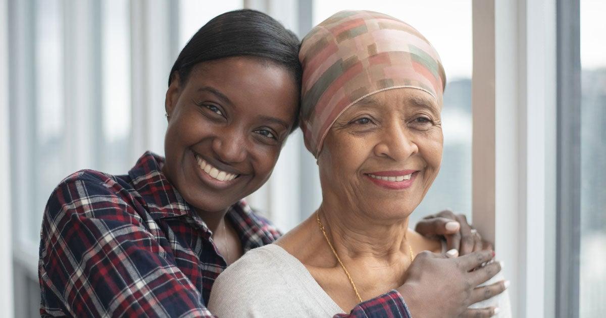 A Black senior woman is being hugged by her caregiver, daughter.