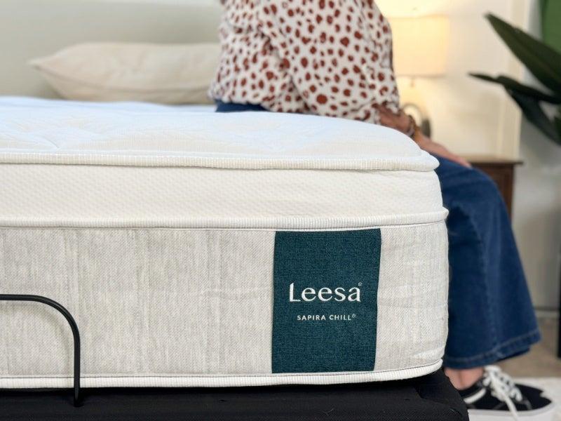 A woman sitting on the edge of the Leesa Sapira Chill mattress