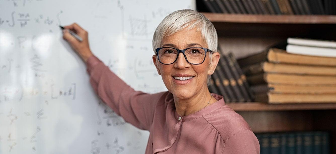 Smiling woman writing equations on whiteboard