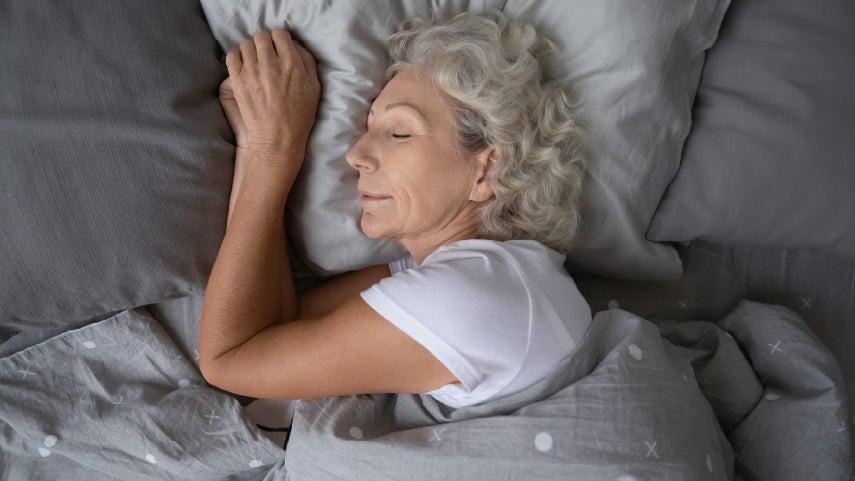 gray-haired woman sleeping on her side, head resting on pillow