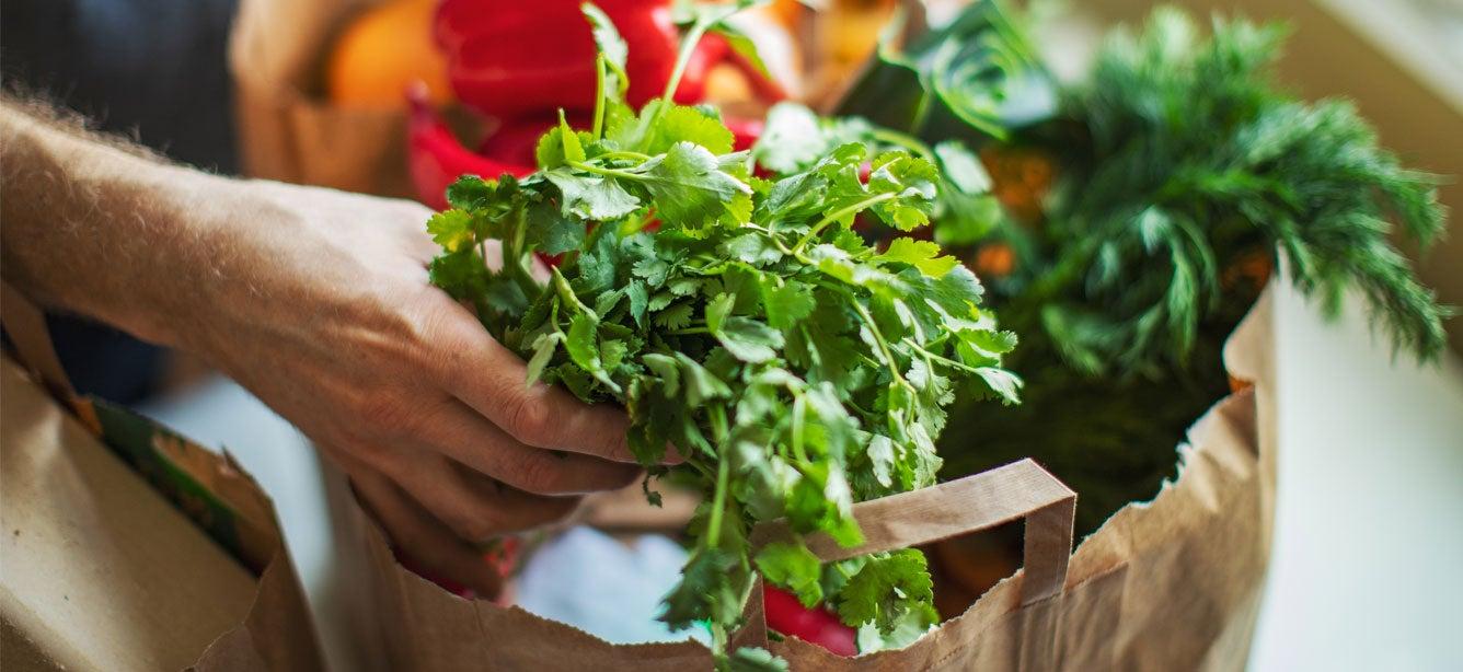 Two bags of groceries filled with fresh produce sit atop a kitchen counter. Thousands of farmers markets across the U.S. now accept SNAP EBT cards for payment. Find out what this means for you.
