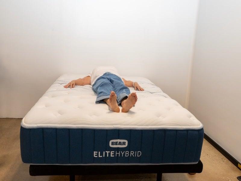 A tester lies on her back on the Bear Elite Hybrid mattress