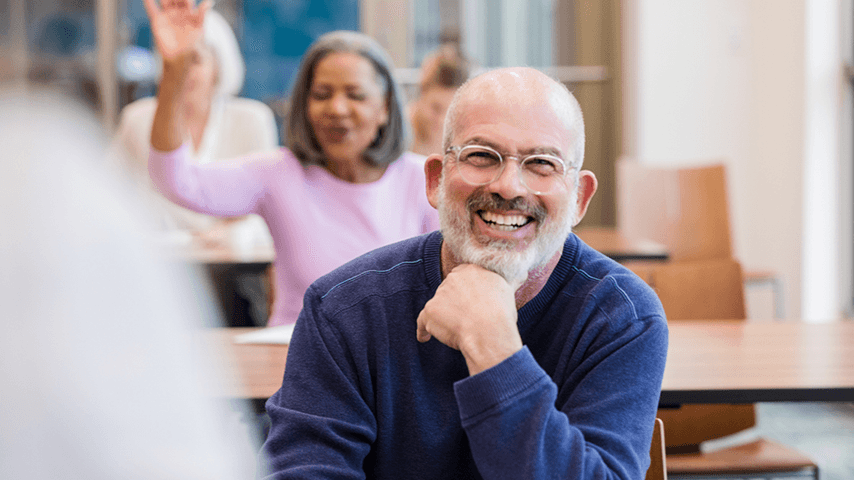 smiling man with gray beard and glasses in classroom