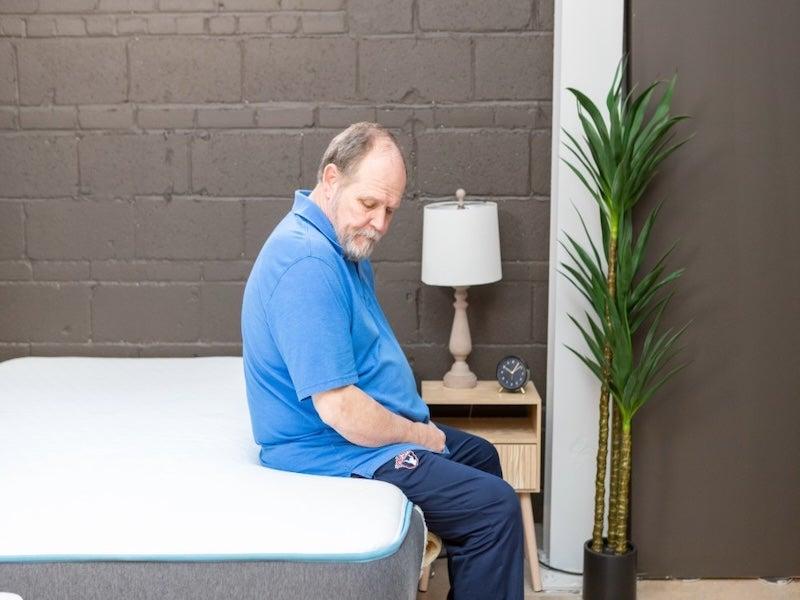 A man sits on the edge of the Brear Original Memory Foam mattress