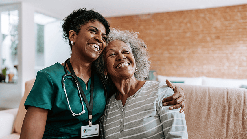 smiling woman doctor with arm around older woman