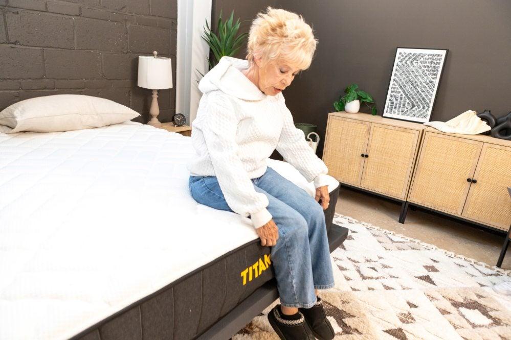 A woman sits on the edge of a mattress