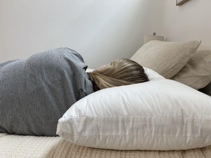 The back of a person lying on their side and resting their head on the Silk & Snow pillow.