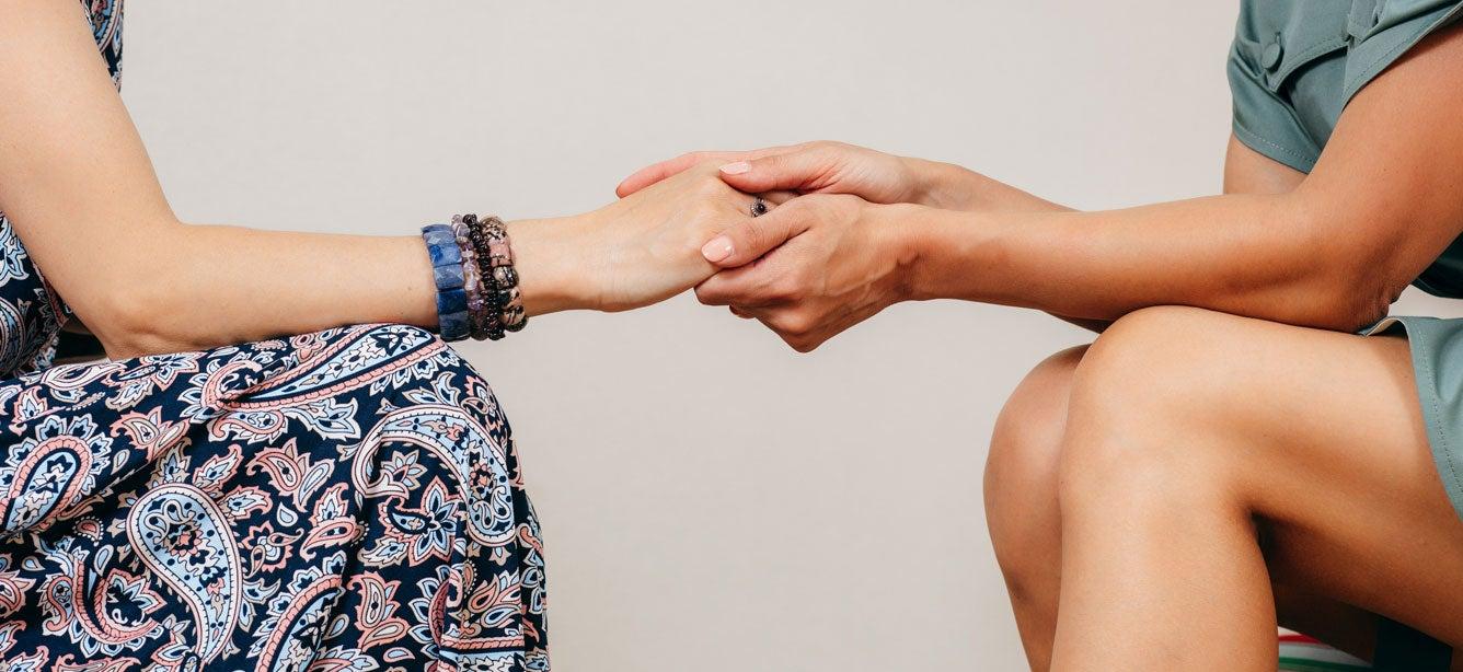 A young caregiver is holding the hand of her older adult grandmother.