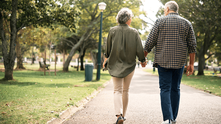 older couple walking holding hands in park