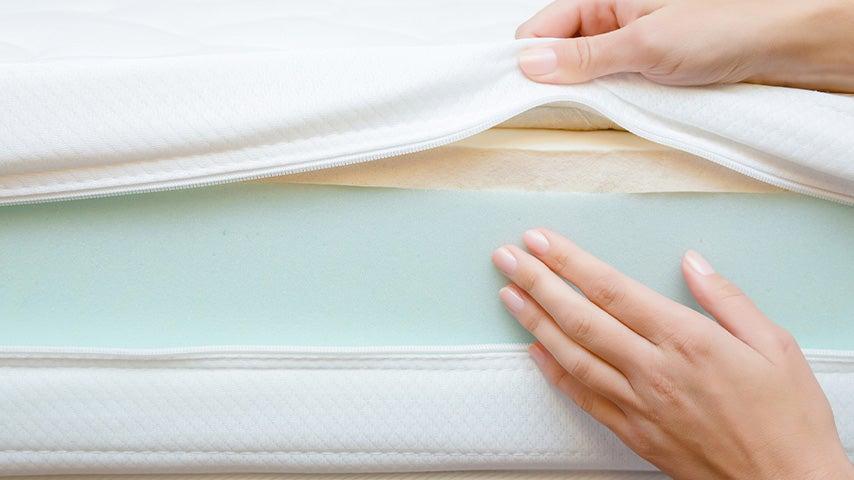 woman's hands pulling back mattress cover to reveal foam layers