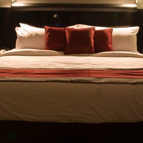 A large bed with a dark headboard and red and white pillows