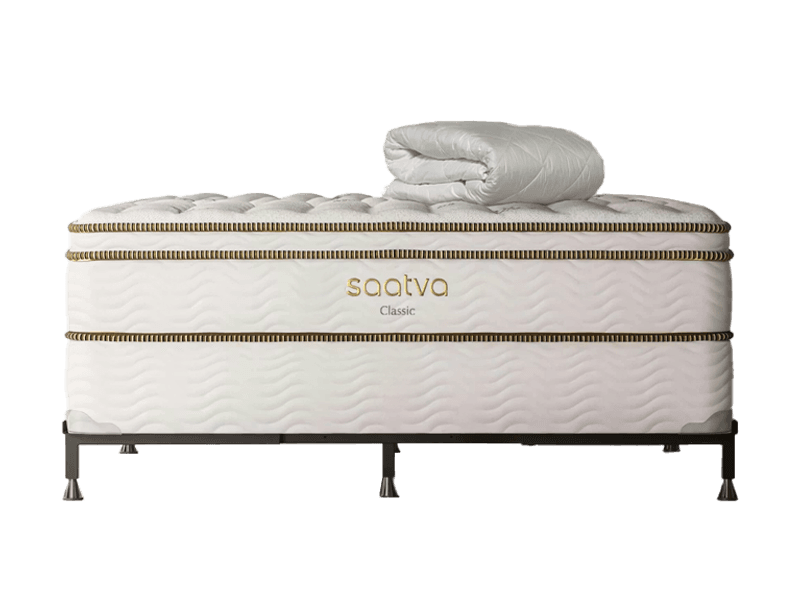 A rolled-up white duvet cover sits atop a Saatva Classic Luxury Firm mattress with no sheets on it