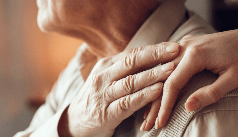 An older man holds a comforting hand on his shoulder