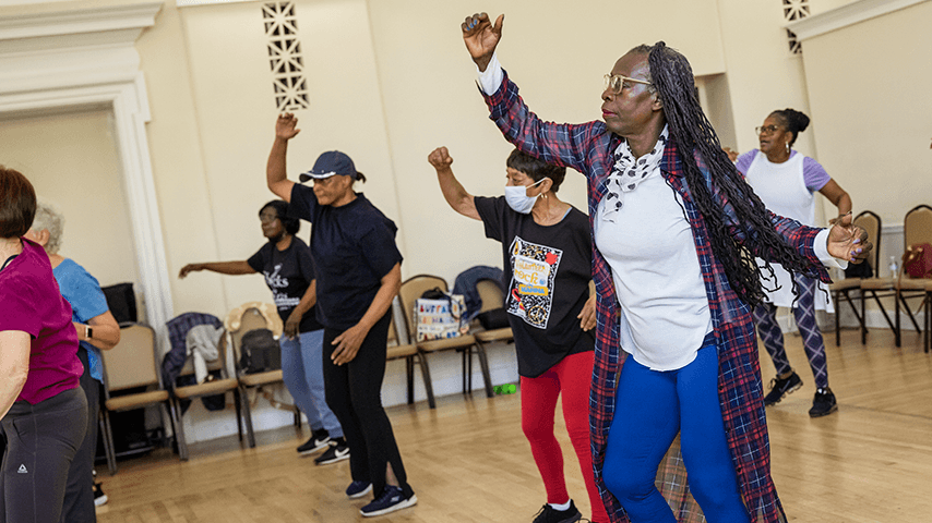 senior center exercise class in wood-floored auditorium
