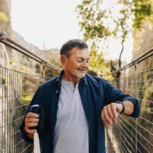 A man looks down at his medical alert smartwatch and smiles