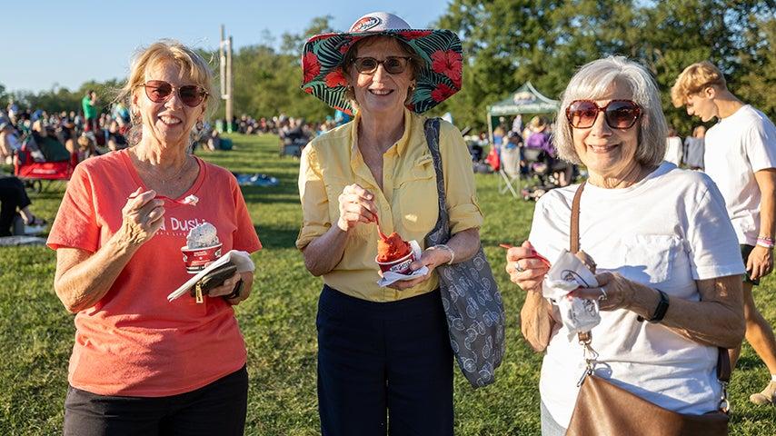 Three women holding ice cream and smiling at the camera.
