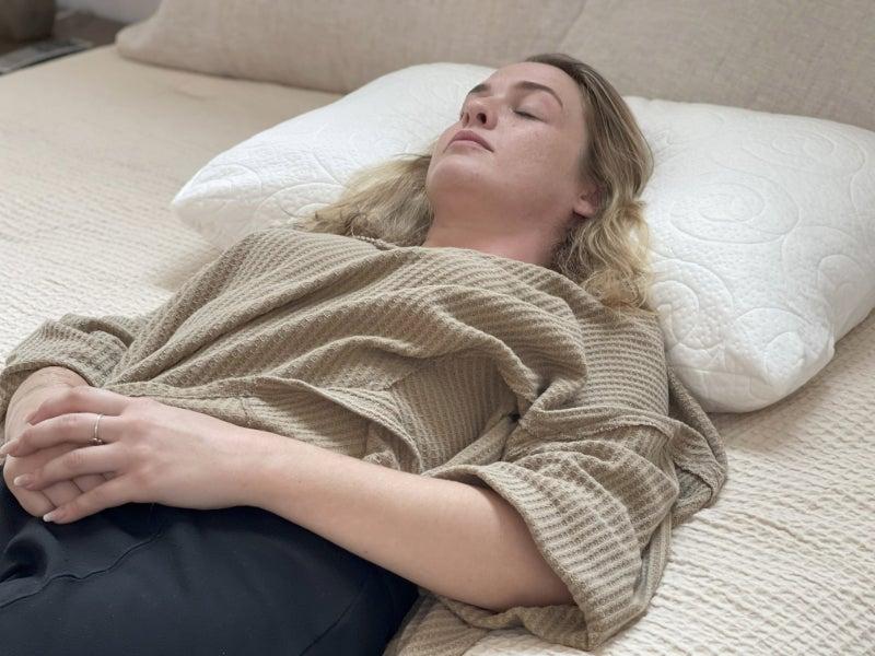 A woman sleeps on her back on the Fox by Lagoon pillow.