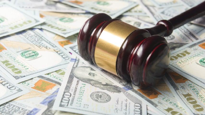 A close up of a gavel laying on top of money.