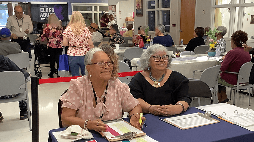 two older women at check-in table for senior center event