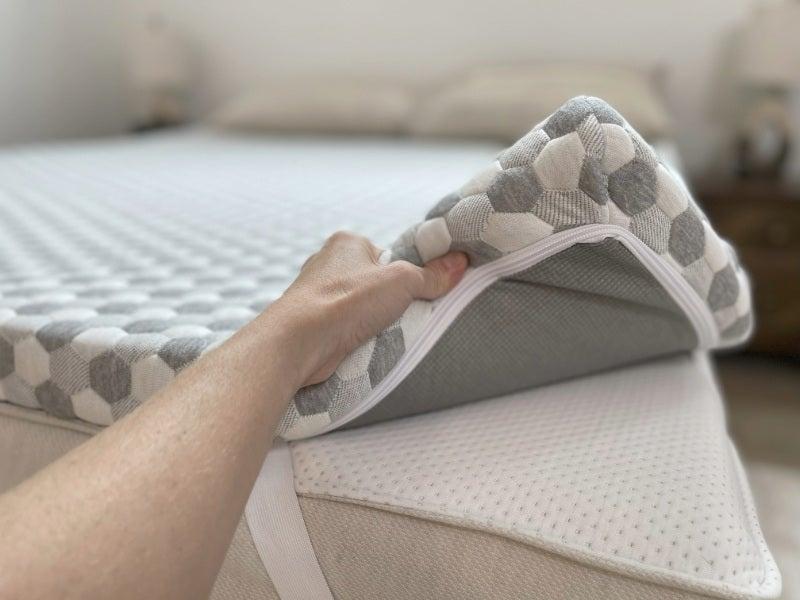 A person displays the fabric and zipper of the Layla mattress topper