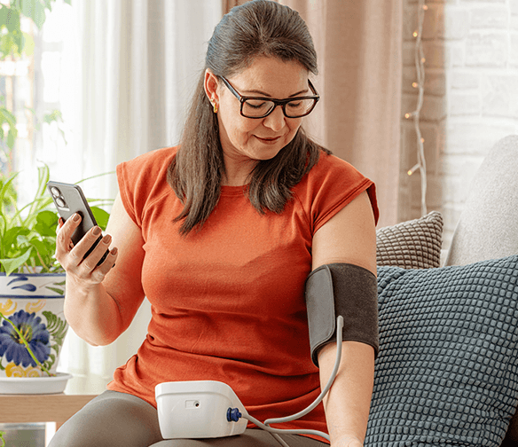 woman taking blood pressure reading while seated on couch