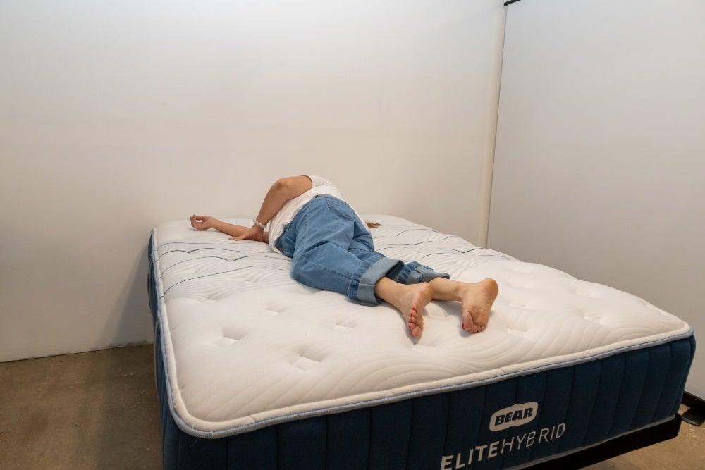 An older woman lying on her side on the Bear Elite Hybrid mattress