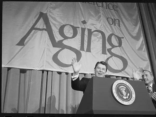 Ronald Reagan in front of White House Conference on Aging banner