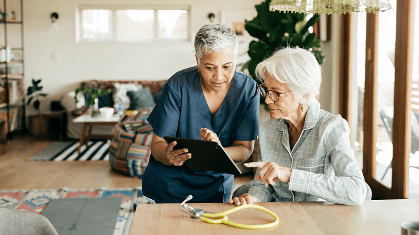 home health nurse showing older woman health stats on a tablet