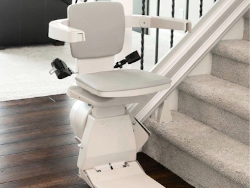 An indoor Bruno stair lift on a straight staircase with grey carpet