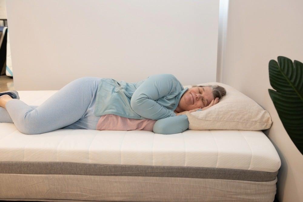 A woman lying on her side on the Helix Plus mattress